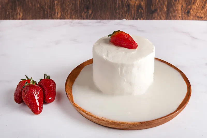 Tres Leches de Fresa individual en plato con orilla de madera, con fresas frescas