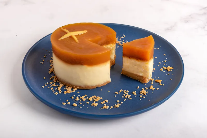 NY Guayaba Cheesecake individual cortado en plato azul, con la capa de guayaba a la vista